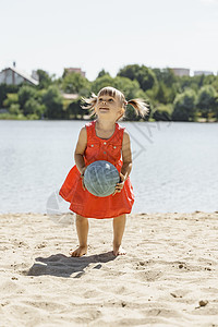 穿红裙子的可爱小女孩 在沙滩上玩球赤脚喜悦玩具礼服活动家庭排球幸福竞赛海滩图片