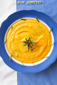 盘子里的南瓜汤奶油餐巾午餐蔬菜食物蓝色橙子制品勺子木头图片