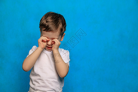 一个蓝色背景的男孩揉了揉眼睛 眼睛健康 眼睛疾病 一个爱哭的婴儿 儿童疲劳 心理学男生童年疼痛眼泪黑色哭泣孩子图片