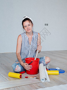 一名坐在房间地板上 用桶子搅拌墙纸胶的妇女的肖像 该公寓的翻修概念 (见E/CN 4/Sub 2/2000/10)图片