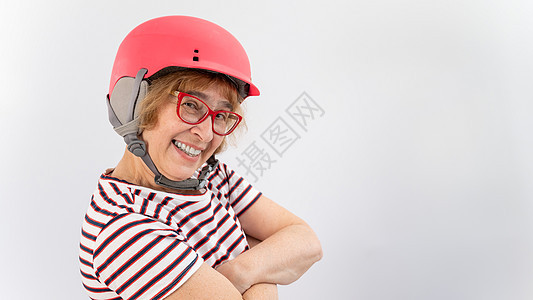 戴护目镜和白背景粉红色滑头盔的快乐老年妇女图片
