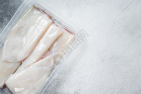 厨房桌上的真空软件包中的新鲜原始 Squid 或 Calamari 白色背景 顶视图 复制空格食物美食香料盒子海鲜乌贼胡椒木板烹图片