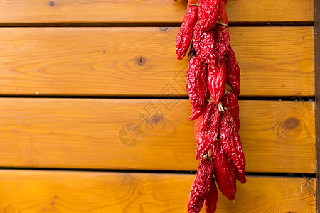 旧木墙背景上的红辣椒 新鲜有机辣椒串挂在外面晒干墙上的干辣椒装饰 著名的匈牙利辣椒图片