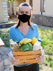 一名身着保护性医疗面具的妇女 在为穷人准备的篮子中装了食品包图片