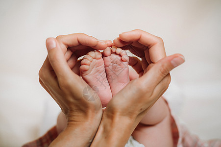 母亲手中新生儿的脚以一颗心的形式举行 孩子们的脚在母亲的手中图片