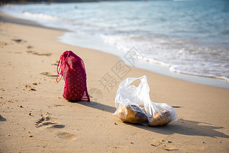 在阳光明媚的一天 海洋沙滩上摆着网状购物袋和塑料袋 海洋生态概念图片