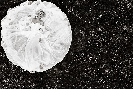 一位穿着白色婚纱躺在地上的美丽新娘的肖像 绿草上一位优雅新娘的照片 新娘的顶级照片 黑白照片图片