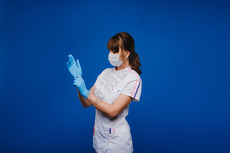 穿戴保护面罩和乳胶或橡胶手套的美丽女医生或护士 在灰色背景上佩戴带复制空间的护身符图片