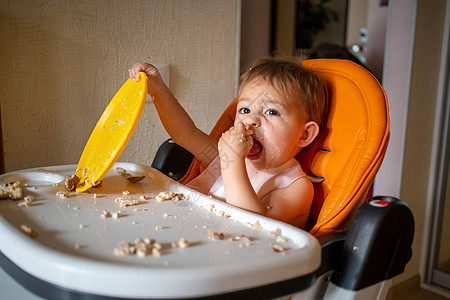 可爱的婴儿在餐桌上玩塑料盘子 小小孩吃完饭后坐在婴儿椅上座位孩子女孩食物男生早餐喜悦桌子食品童年图片