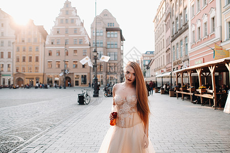 穿着长发婚纱和酒瓶的新娘在老城沃克劳 在一个波兰古城市中心举行婚礼照片拍摄 波兰弗罗克瓦夫Wroclaw建筑学饮料景点火车肩膀瓶图片