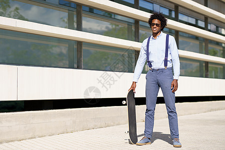 黑人男性工人站在有滑板的办公楼旁边 (笑声)图片