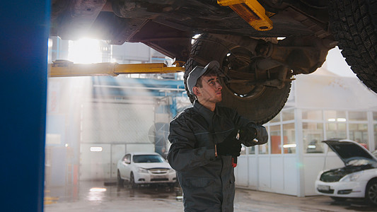 车库汽车服务-汽车底部的机械师检查车轮图片