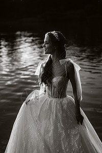穿着白色礼服的优雅新娘在日落时享受自然 在公园里 身着彩礼服的模范黑白照片婚纱女士若虫瀑布幸福赤脚婚姻女孩黑发图片