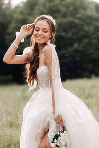 在婚礼当天 一位穿着白色长裙和手套 手上拿着花束的优雅新娘站在一个享受自然的空旷地里 白俄罗斯裙子花朵赤脚婚纱幸福山河若虫婚姻瀑图片
