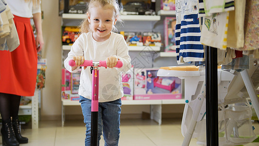 快乐的小女孩在儿童商店里玩自行车图片