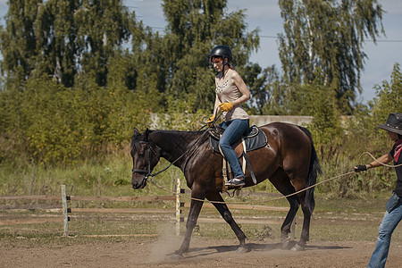 骑马课程骑马的年轻女子头盔马甲棕色女骑士享受森林骑士活动马背骑术图片