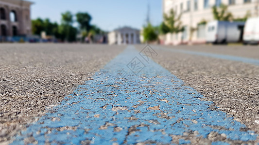 沥青黑色表面上的蓝色宽条纹 城市的柏油路 夏天 绿树 蓝天 从中间蓝线的低角度视图活力马路路面柏油旅行交通车道线条运输街道图片