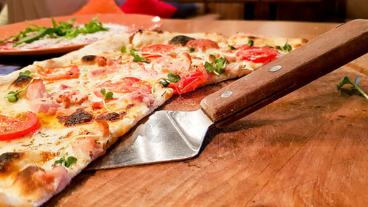 在餐桌上餐厅的木板上 拿着一小片美味意大利比萨饼在一块饭桌上图片