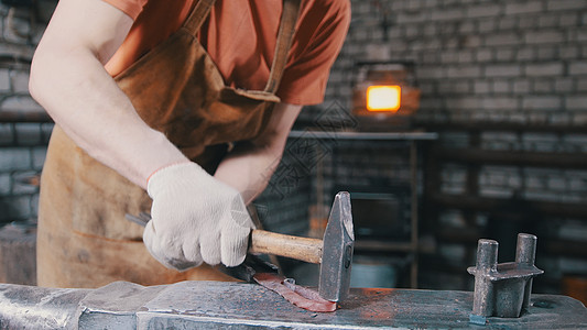 铁匠用锤子使一个红热金属物体成形罢工男性橙子辉光工艺男人劳动艺术运动金工图片