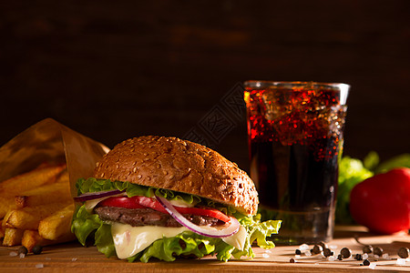 美式零食加大汉堡包和木桌上的玻璃可乐图片