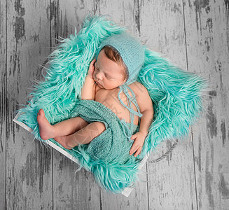 睡在床上的美丽新生婴儿 带毛绒绿宝石毯子图片
