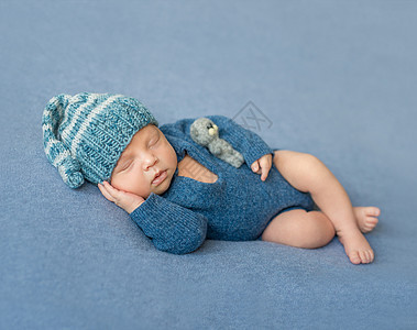 穿着蓝色衬衣和帽子的睡着新生婴儿梦幻休息姿势童年尿布毯子襁褓皮肤男生说谎图片
