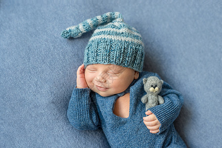 穿着蓝西装和戴玩具帽子的睡着新生儿图片