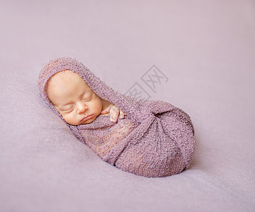 可爱的新生儿在粉色尿布中卷叠图片