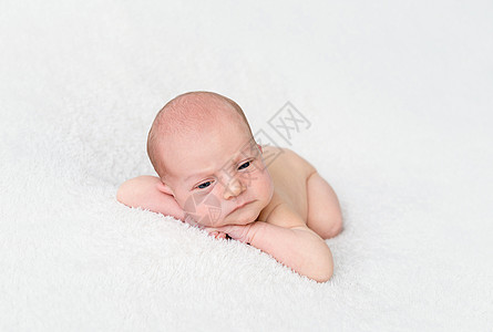 新生婴儿男孩躺在白毯子上图片