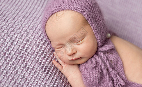 穿着紫色编织帽子的可爱小女孩 睡在她身旁图片