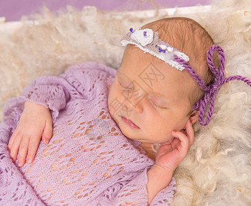 甜甜的新生儿睡在紫罗兰背景的平方小床上戏服紫色生活童年帽子婴儿皮肤女孩孩子婴儿床图片