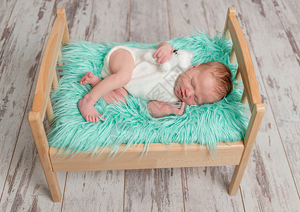 美丽的睡着婴儿用绿绿毯子在木床上睡觉图片