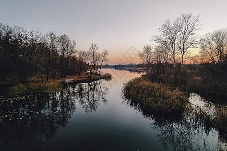 生动的秋天日落 日落秋天风景在河的与光亮的草在岸上 明亮的夜晚风景秀丽 天空五彩缤纷晴天叶子季节森林射线太阳池塘日出反射地平线图片