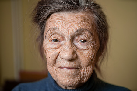 90 岁的可爱老妇人 头发花白 脸上有皱纹 穿着毛衣 肖像很大 微笑着 看起来很快乐 房间的背景 主题长肝抗衰 老人心情好病房老图片