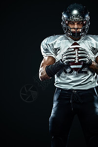 美国橄榄球运动员球员在黑色背景上的头盔 运动和动力 团队竞技大学联盟黑暗足球体育场挑战行动力量竞赛游戏图片