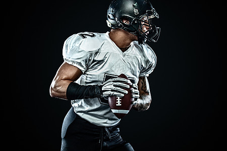 美国橄榄球运动员球员在黑色背景上的头盔 运动和动力 团队竞技行动体育场挑战玩家游戏大学竞赛黑暗训练赛跑者图片