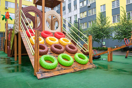一个高层建筑的庭院 在一个没有人的雨天 有一个由木头和塑料制成的现代大型游乐场 空荡荡的户外游乐场 儿童游戏和运动的场所院子操场图片