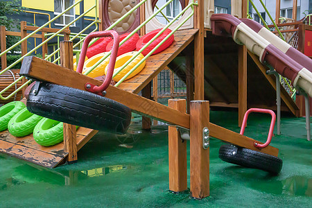 一个高层建筑的庭院 在一个没有人的雨天 有一个由木头和塑料制成的现代大型游乐场 空荡荡的户外游乐场 儿童游戏和运动的场所孩子活动图片