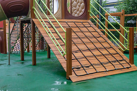 一个高层建筑的庭院 在一个没有人的雨天 有一个由木头和塑料制成的现代大型游乐场 空荡荡的户外游乐场 儿童游戏和运动的场所城堡梯子图片