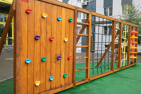 一个高层建筑的庭院 在一个没有人的雨天 有一个由木头和塑料制成的现代大型游乐场 空荡荡的户外游乐场 儿童游戏和运动的场所娱乐梯子图片