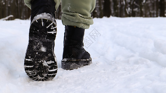 穿着黑色靴子的女性腿 冬天在雪地里行走 活跃的女人在冬天的森林里从镜头前走开 专注于你的腿 美丽的白色冬季天气与新鲜的降雪季节女图片