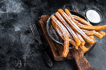 墨西哥传统甜甜点 churros 带糖粉在锅中 黑色背景 顶视图 复制空间乡村美食食物甜点棕色肉桂油炸粉末面包糕点图片