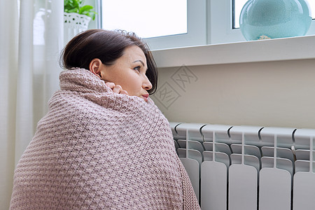 冬天 采暖季 穿着暖和毛衣的女人坐在暖气散热器附近的房间里温暖金属女性女士温度预算房子加热器毯子家庭图片