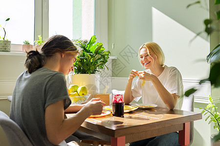 青少年男女用果酱吃煎饼 坐在家里的桌子上男性微笑朋友们营养烹饪食物孩子女性快乐友谊图片