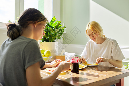 青少年男女用果酱吃煎饼 坐在家里的桌子上早餐烹饪食物男性孩子女性微笑友谊童年朋友们图片