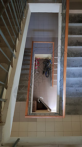 在住宅楼的现代楼梯间 透视楼梯 灰色瓷砖 带有棕色木栅栏和混凝土台阶的公共楼梯 从上面看公寓扶手运动多层护栏梯子入口建筑学房子螺图片