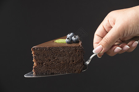 握着巧克力蛋糕切片的手图片