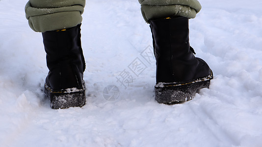 穿着黑色靴子的女性腿 冬天在雪地里行走 活跃的女人在冬天的森林里从镜头前走开 专注于你的腿 美丽的白色冬季天气与新鲜的降雪公园皮图片