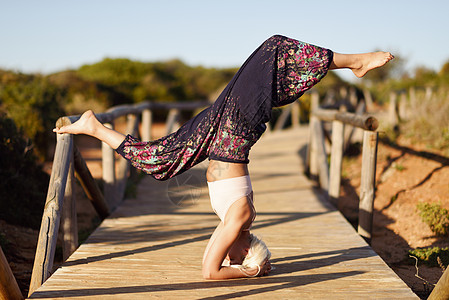 白种女性在木桥上练瑜伽女士幸福天空平衡杂技成人金发女郎专注姿势海滩图片