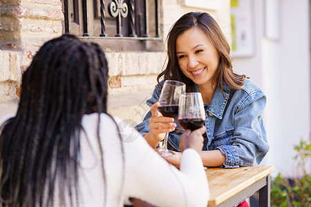 两个女人在酒吧外的桌子上 喝红酒敬酒喜悦学生庆典幸福爆炸快乐辫子乐趣酒精女孩图片